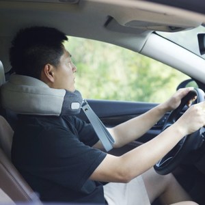 Driver wearing a portable neck massager while traveling